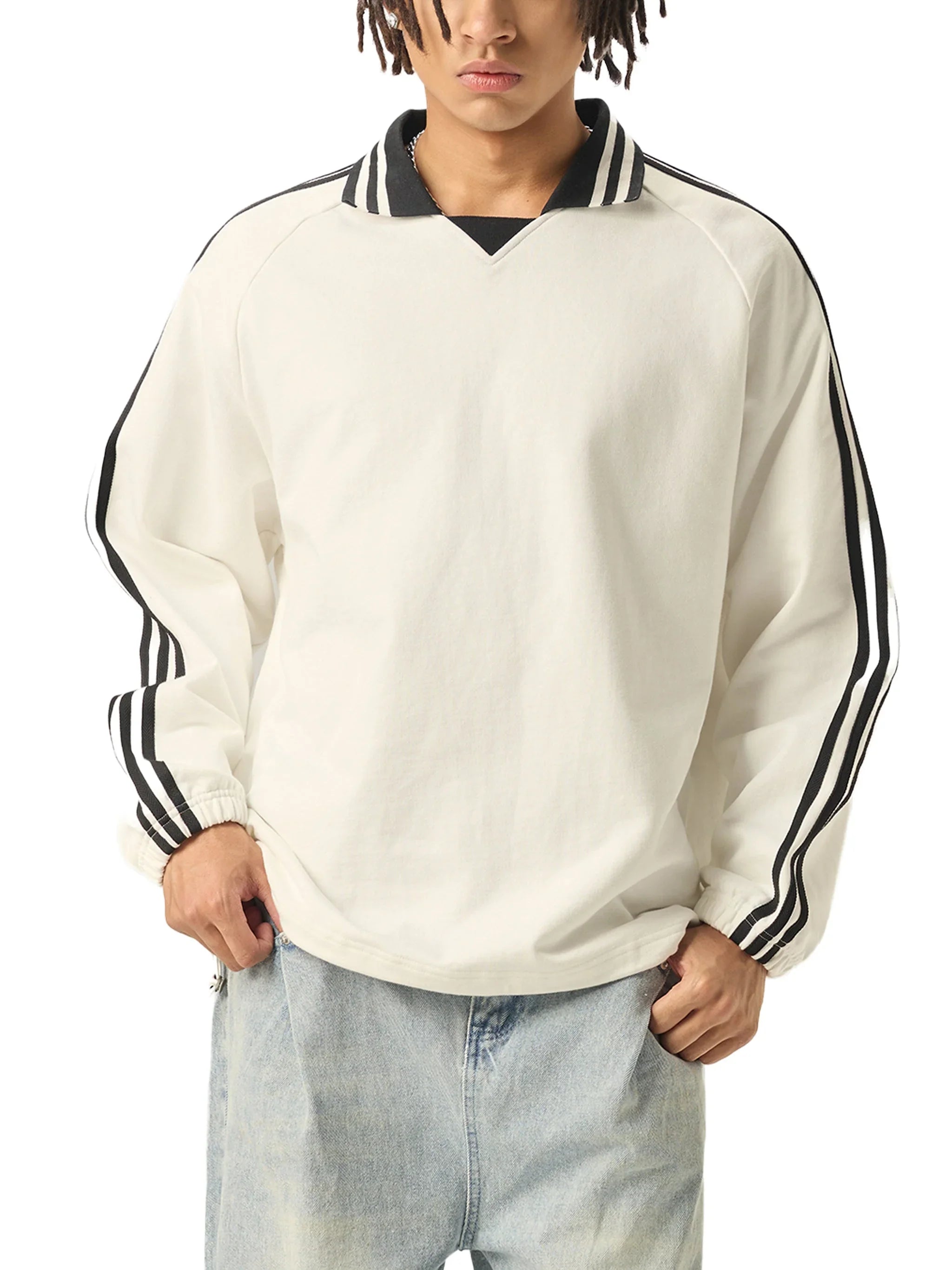 Man wearing a white pullover with black striped collar and sleeve accents, paired with light wash jeans