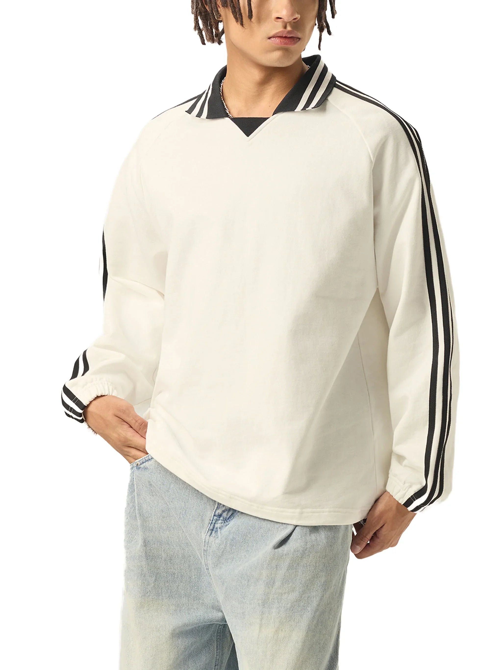 Man wearing a white heavyweight pullover with black striped collar and sleeves, paired with light wash jeans.