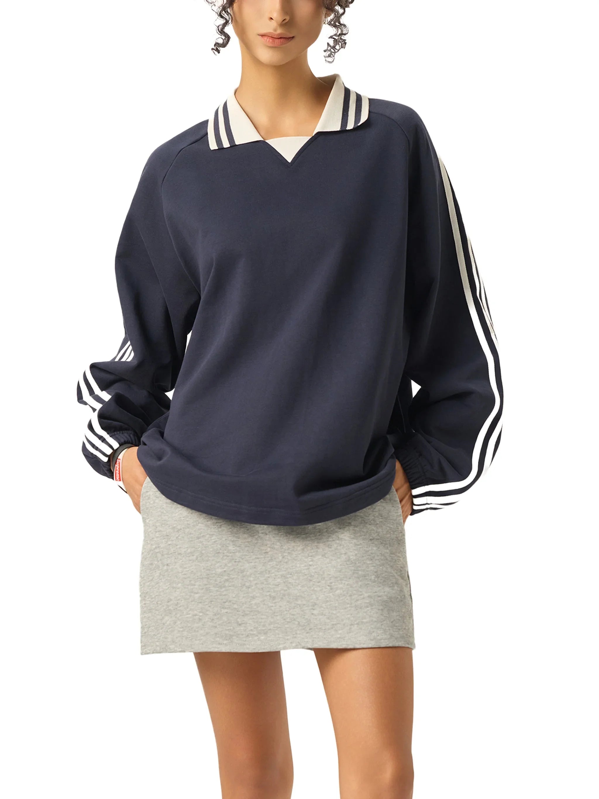 Woman wearing navy heavyweight sweatshirt with striped collar and sleeves, grey mini skirt
