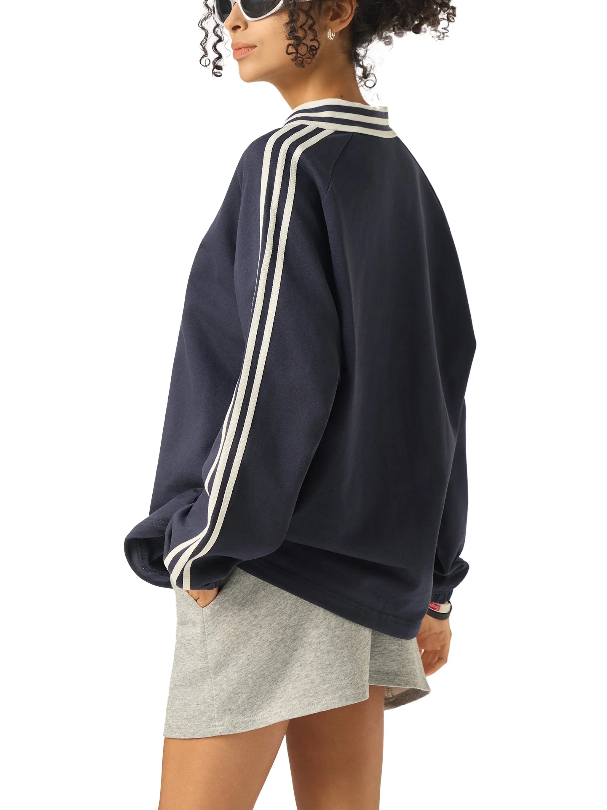 Woman wearing navy blue streetwear sweatshirt with white stripes and gray shorts