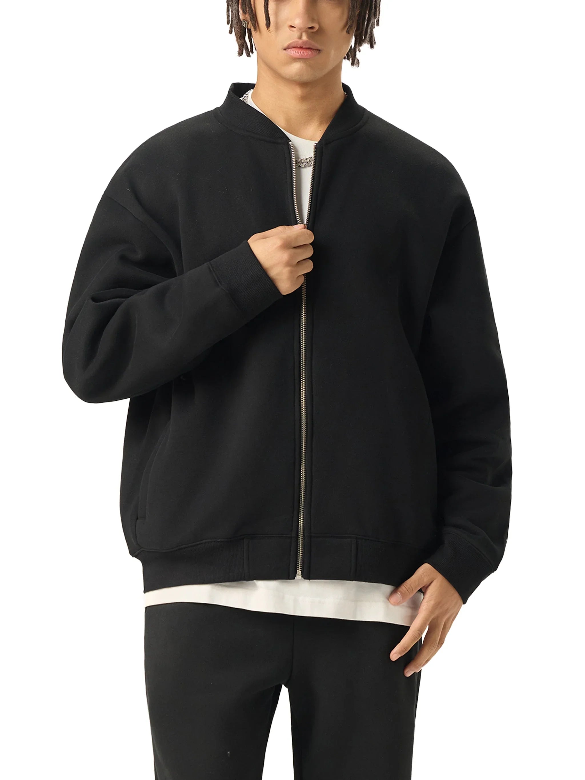 Man wearing black zip-up bomber jacket over white shirt and black pants, streetwear style