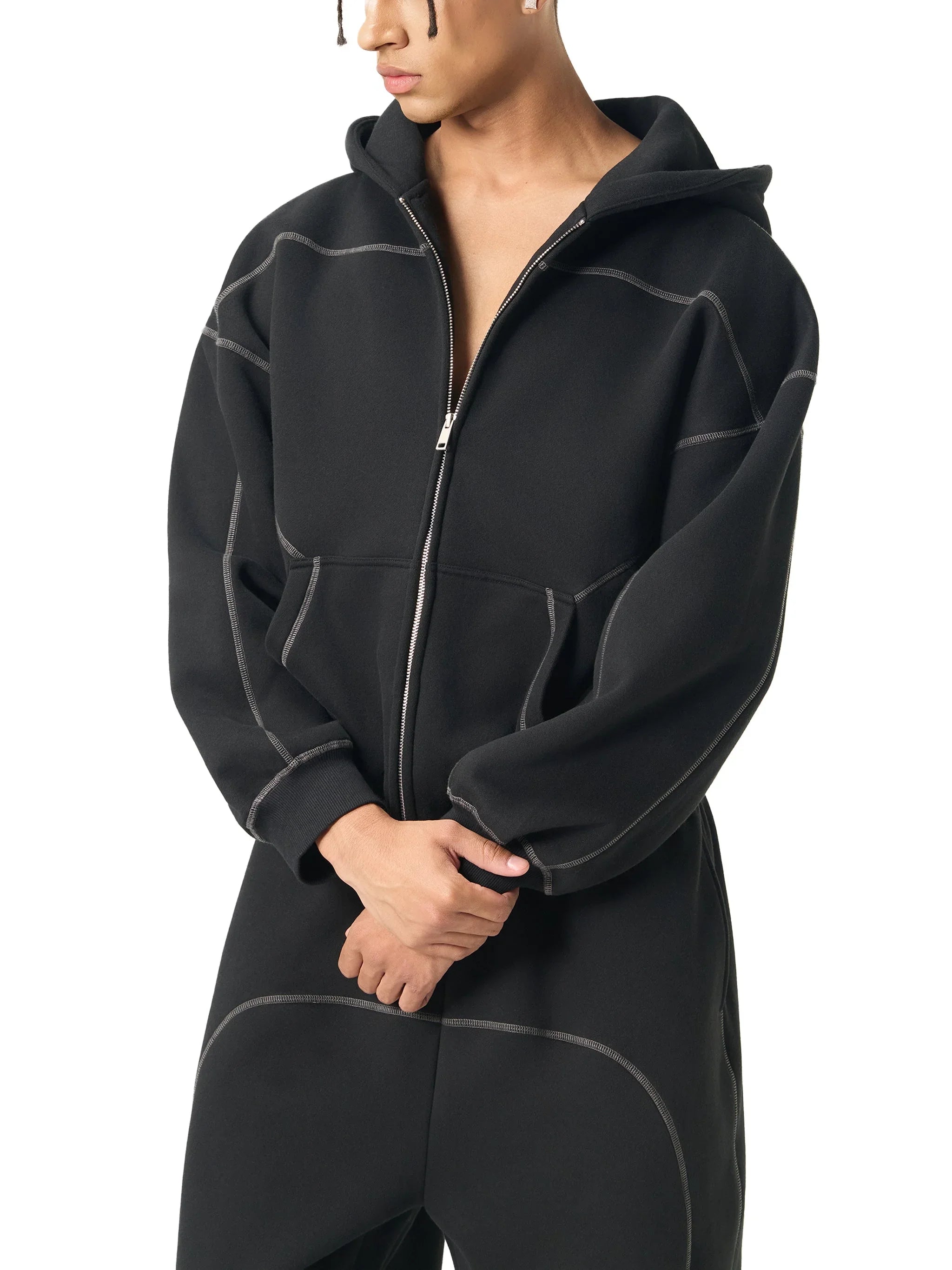 Man wearing a heavyweight black zip-up hoodie with contrast stitching, streetwear style
