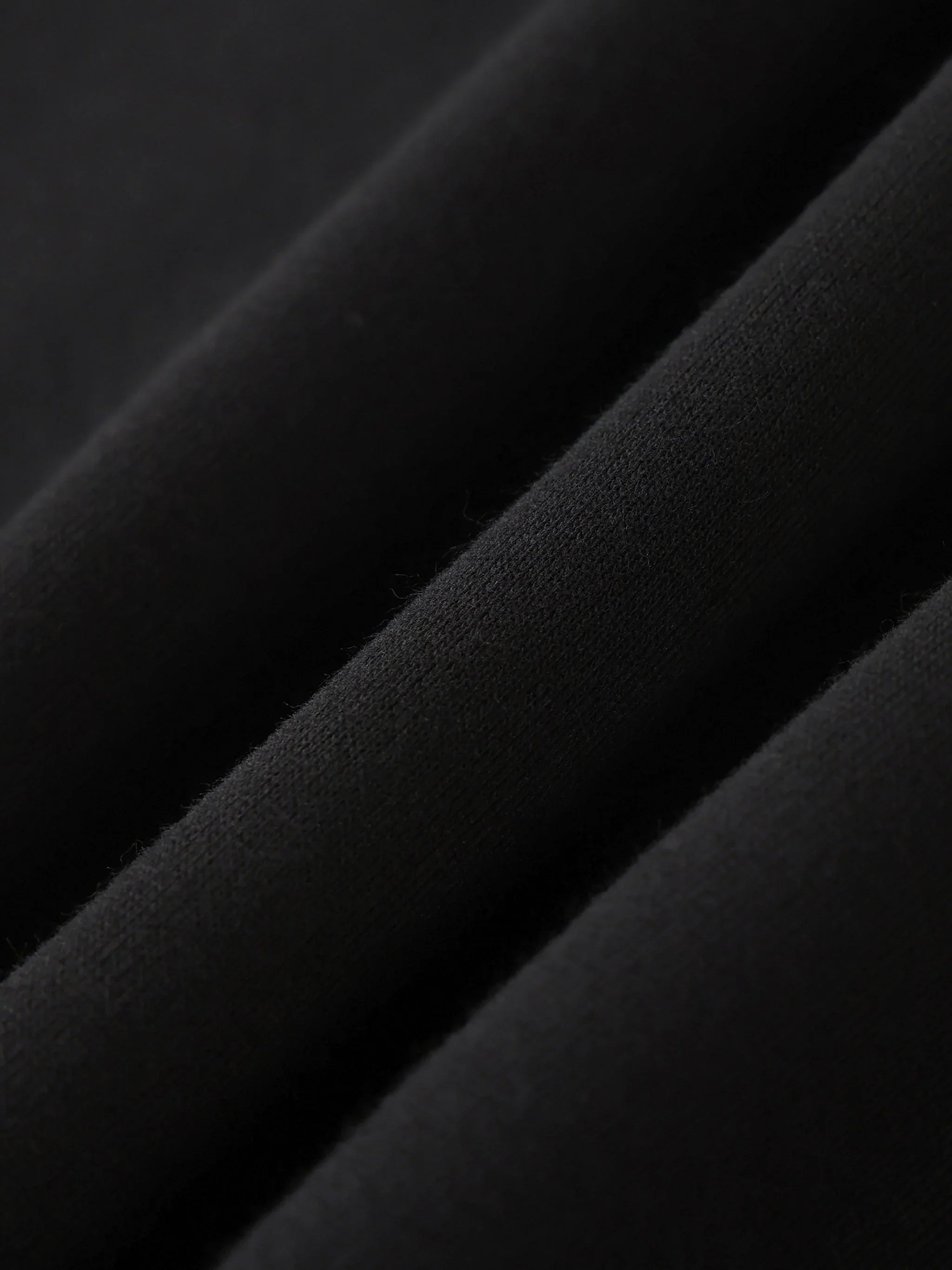 Close-up of black heavyweight cotton fabric, showing soft texture and premium quality
