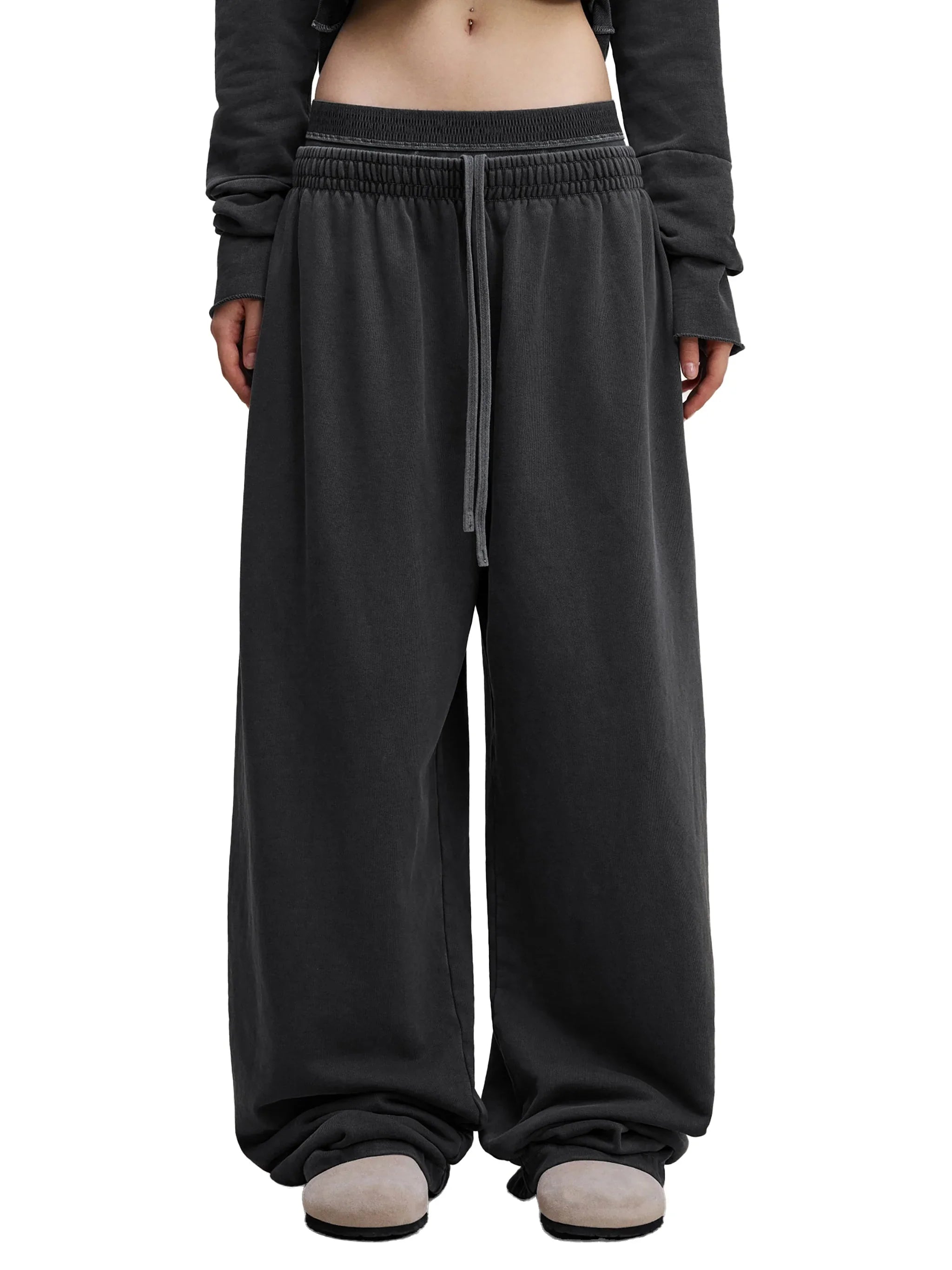 Oversized black sweatpants with elastic waistband and drawstring, styled for streetwear fashion