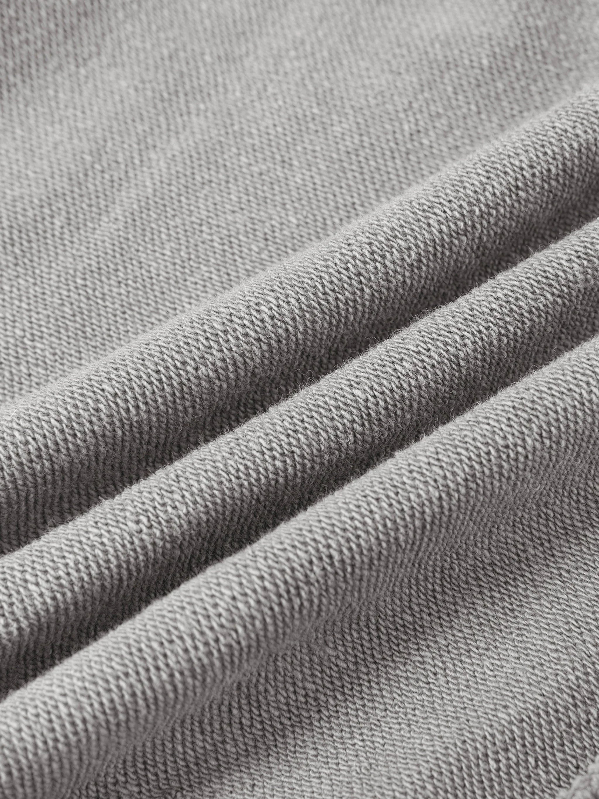 Close-up of grey heavyweight knit fabric with soft texture and folded layers